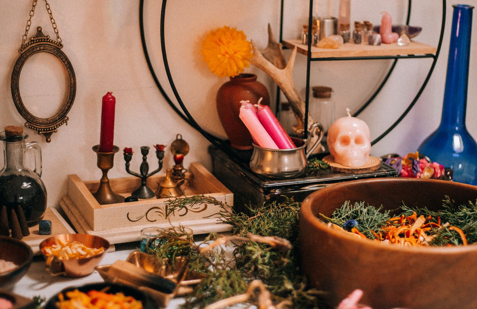 A home altar set with candles, dried herbs in a wooden bowl, and ritual tools