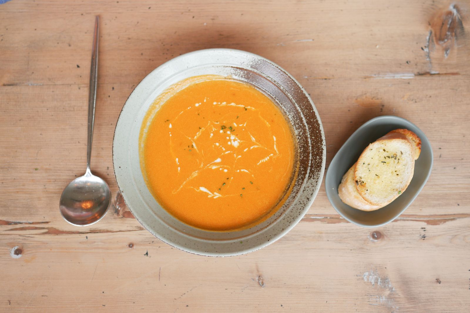Pumpkin soup with canned pumpkin in a bowl beside bread on a wooden table