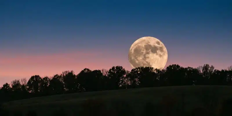 Supermoon rising over a wooded hill at dusk Plentiful Earth | Global Spirituality A large full moon rising behind a line of trees on a hill at dusk under a blue and rose sky