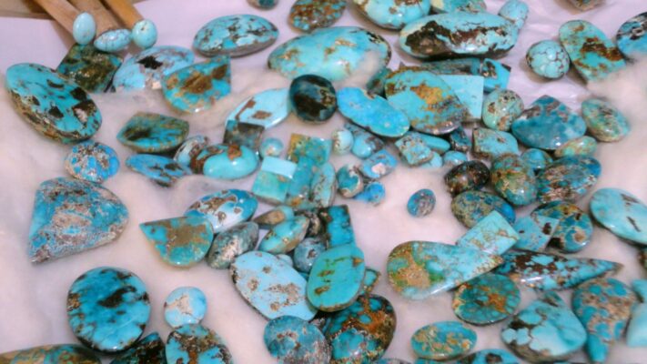 turquoisemeaningnishapur Plentiful Earth | Global Spirituality Assorted turquoise stones and pebbles with brown veining scattered on a light surface.