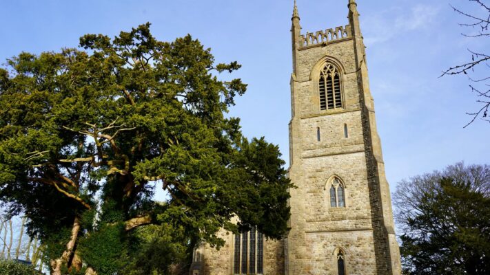 yewtreechurch Plentiful Earth | Global Spirituality An ancient yew tree with a broad dark green crown beside an old stone church tower in England.